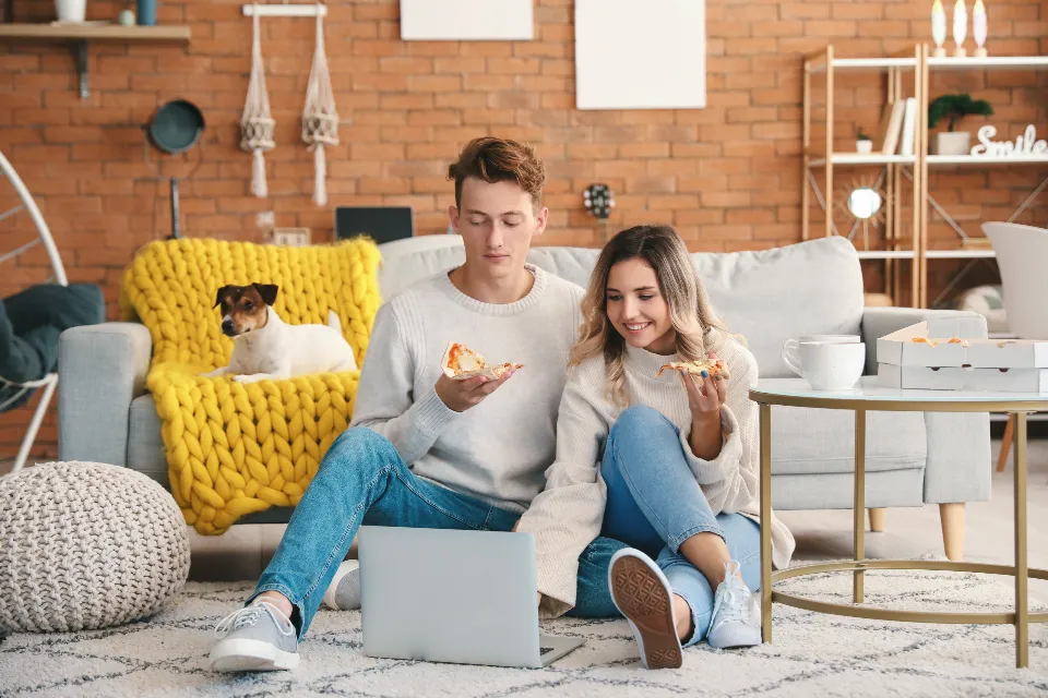 Un couple assis dans son salon consulte un ordinateur portable